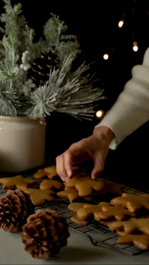 someone decorating some cookies together with pine cones