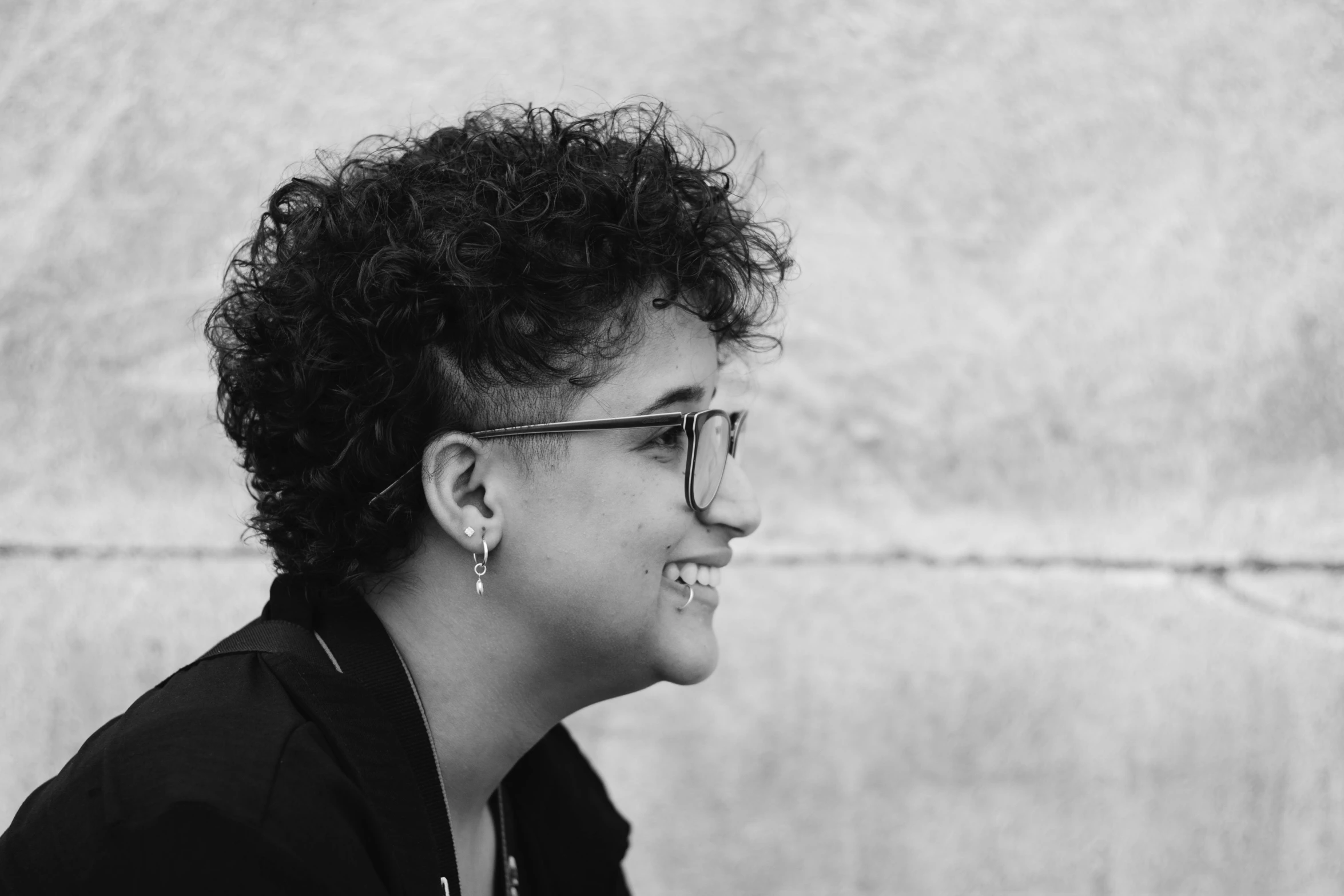 a smiling woman wearing glasses looking away from the camera