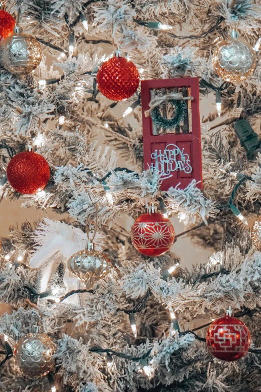 a christmas tree has a red plaque, balls, and a tree ornaments