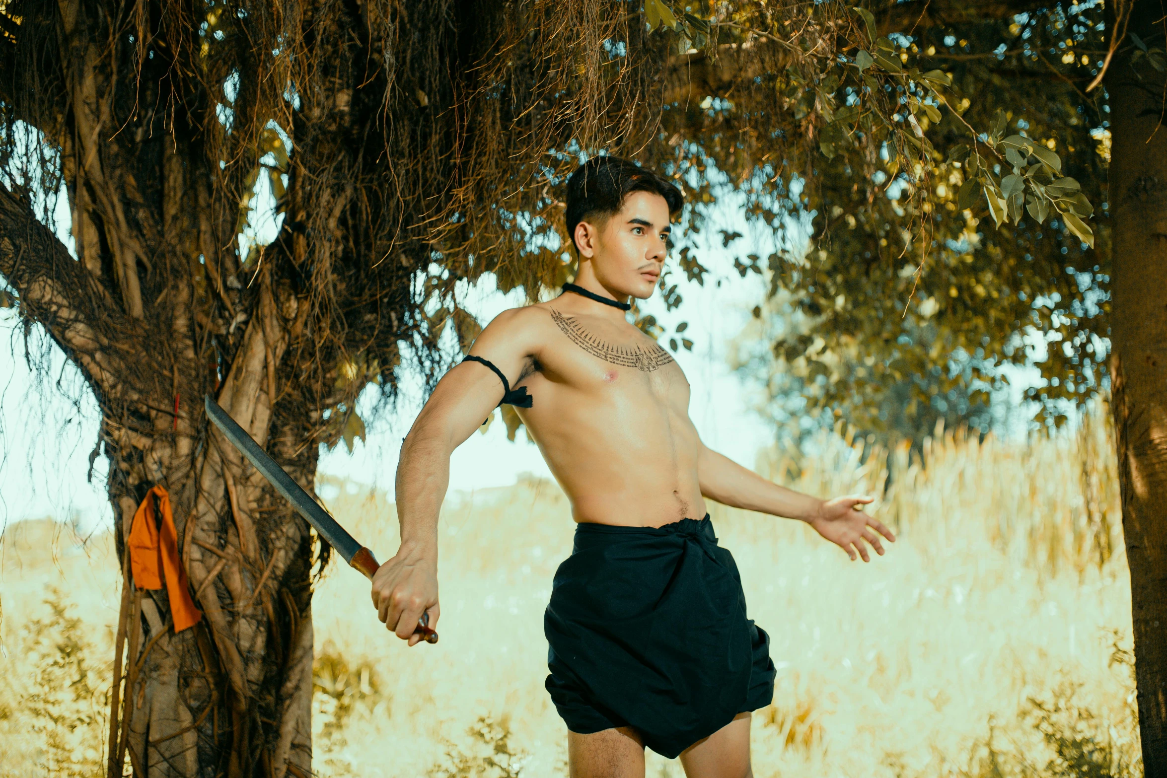 a shirtless man holding onto an odd object in a forest