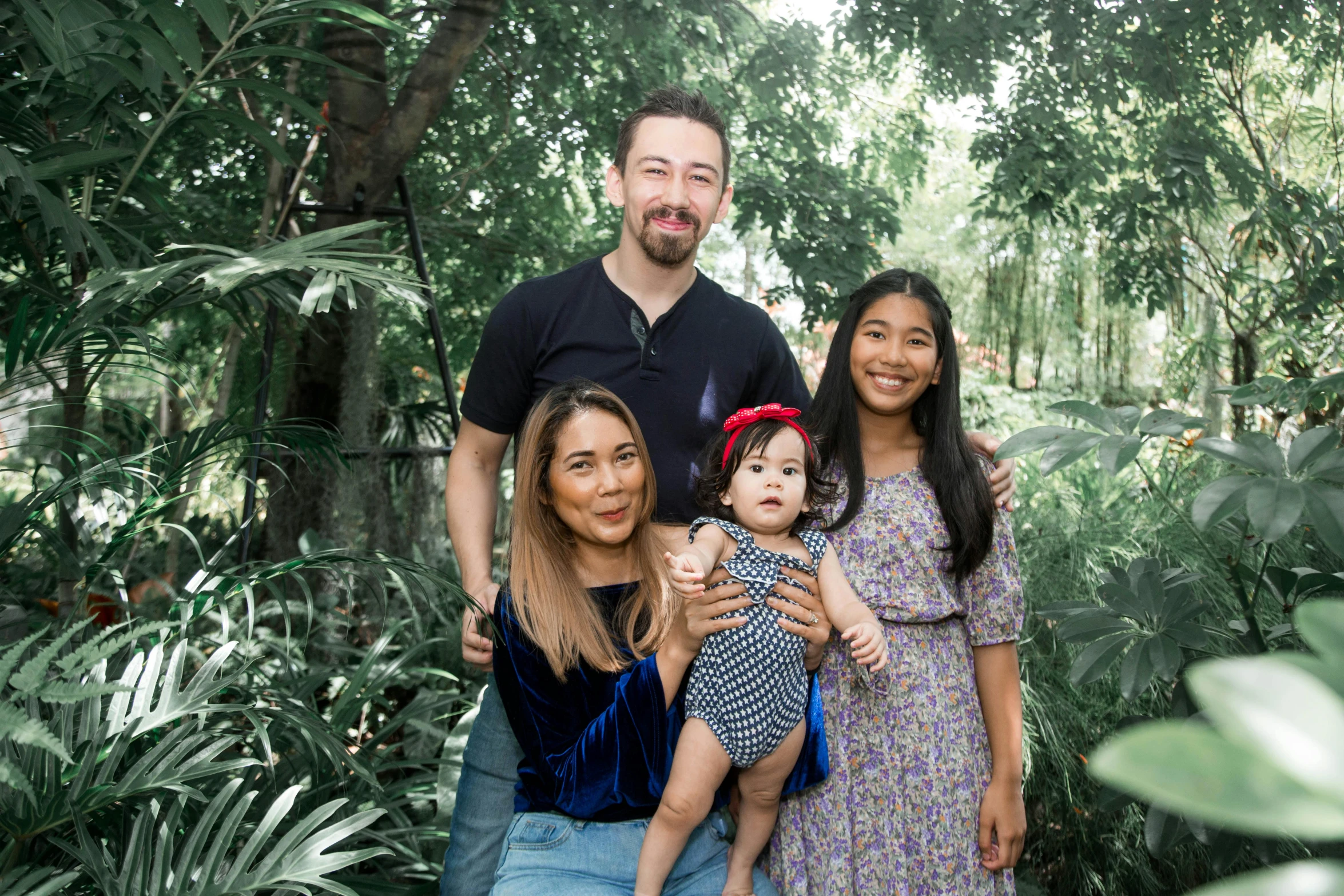 a father standing next to his two daughters in a forest