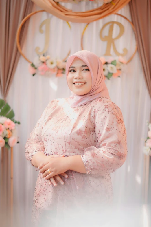 a beautiful woman wearing a hijab standing in front of flowers