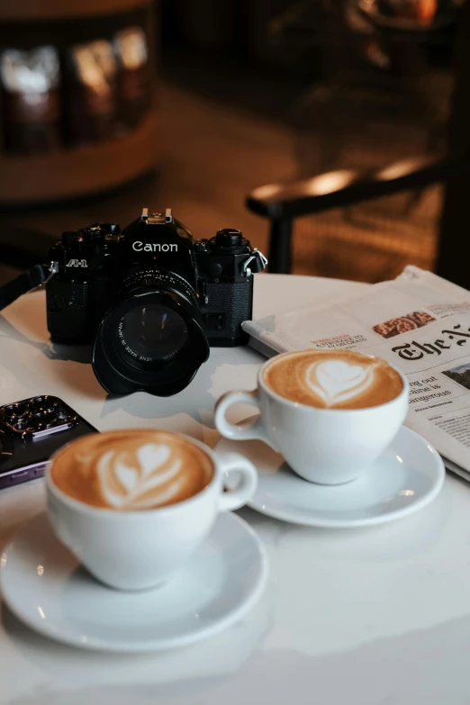 two cups of coffee sitting on a plate with an advertit for canon on it