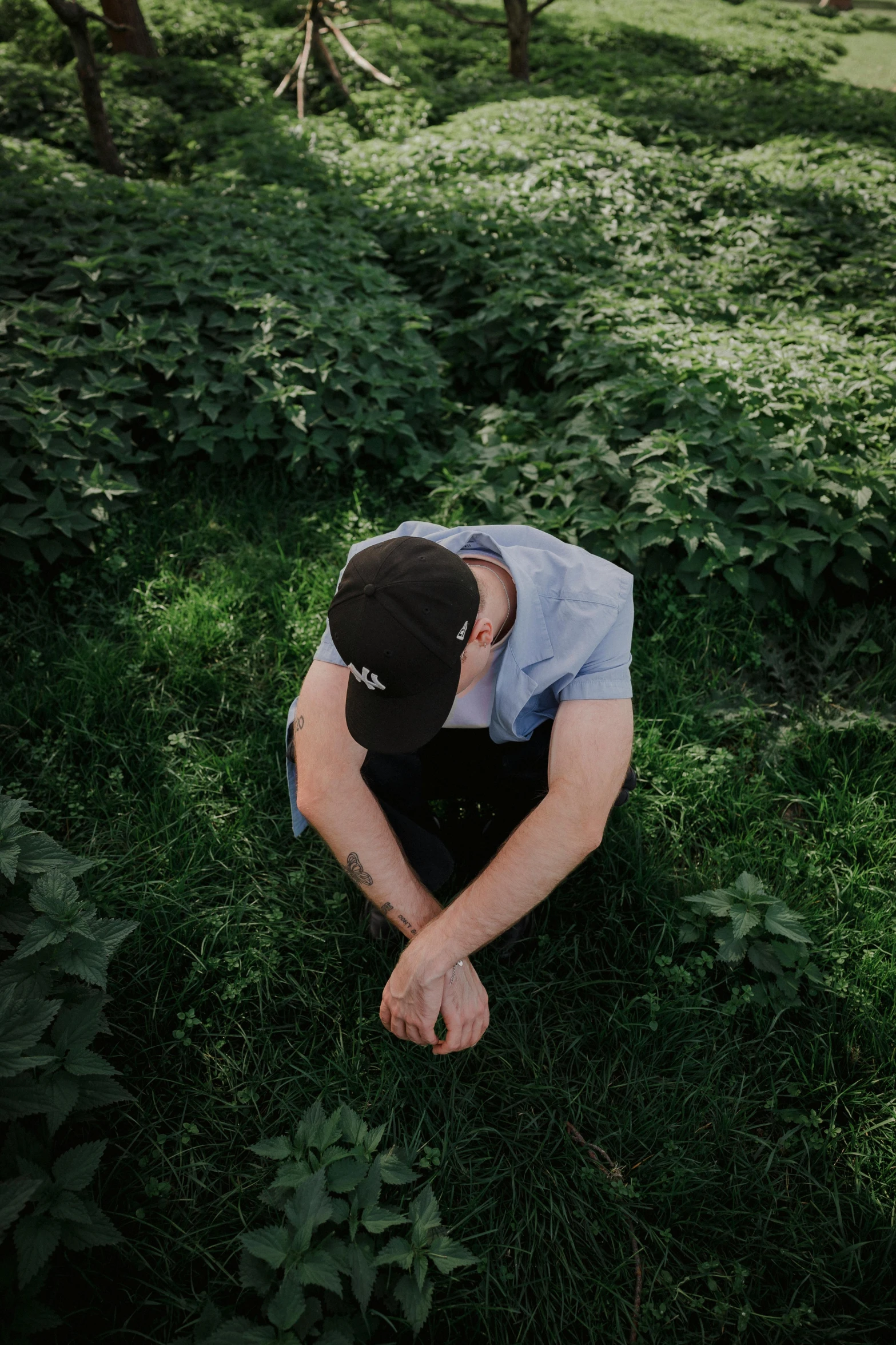 a young man sitting on a lush green hillside