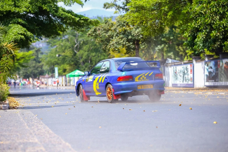 an older sports car on the road with yellow stripes