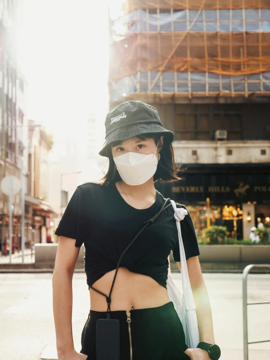 the woman in a hat is holding a cell phone and wearing a face mask