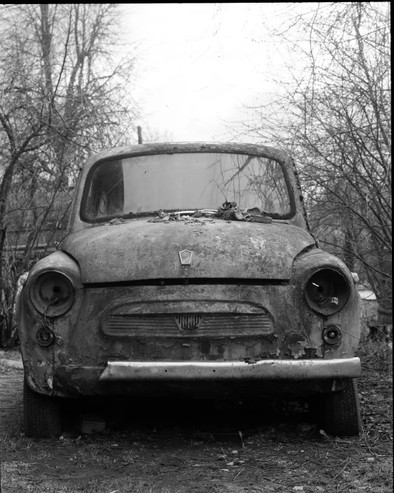 a rusted up truck parked in a field with trees