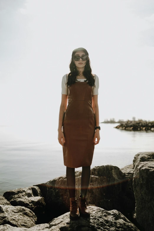 a woman standing on a large rock in front of the ocean