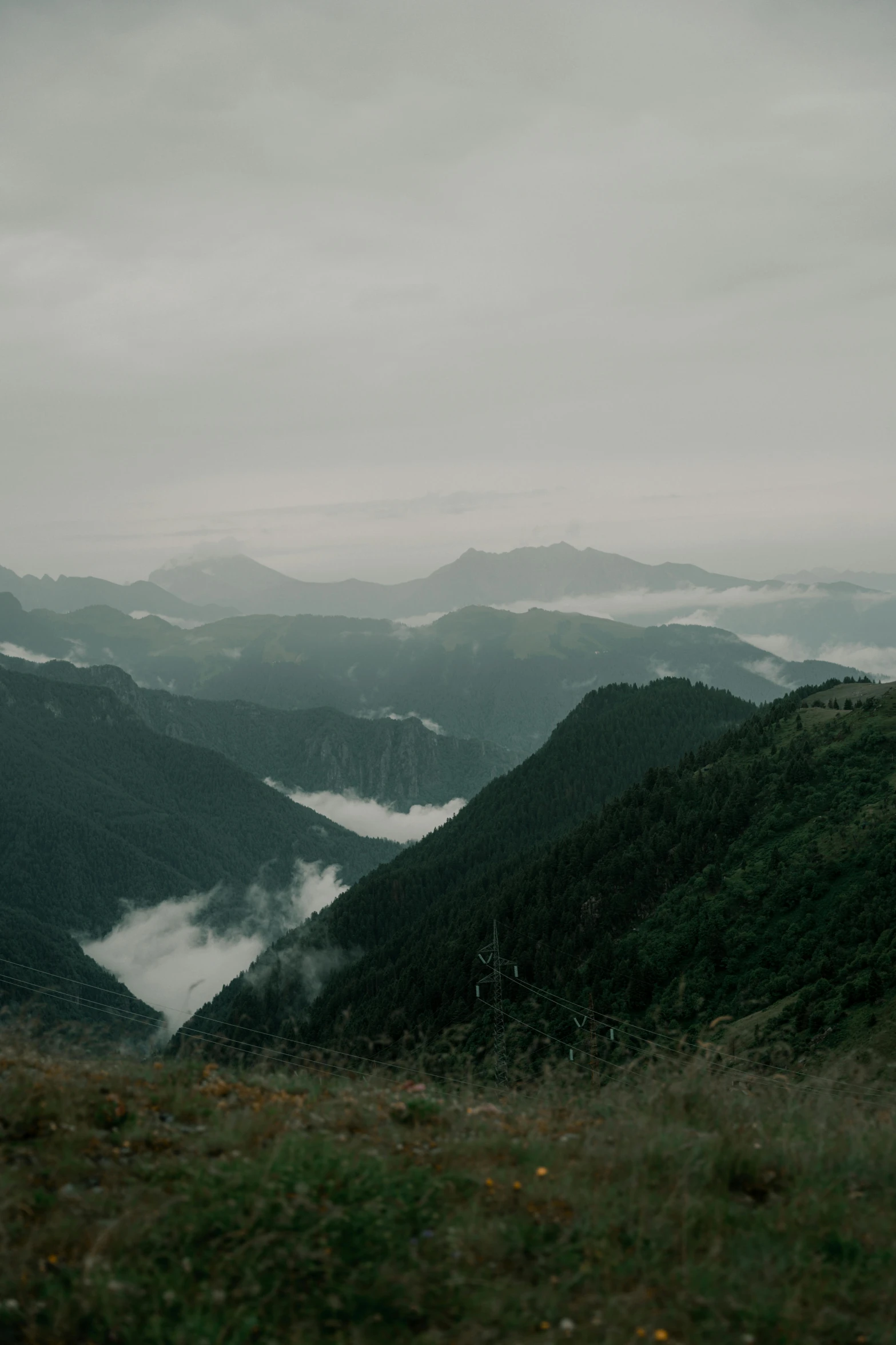 a lush green hillside covered in clouds, surrounded by tall hills