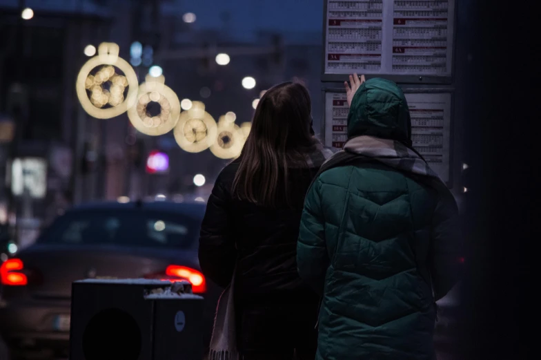 a couple stands on the side of the road looking at a wall