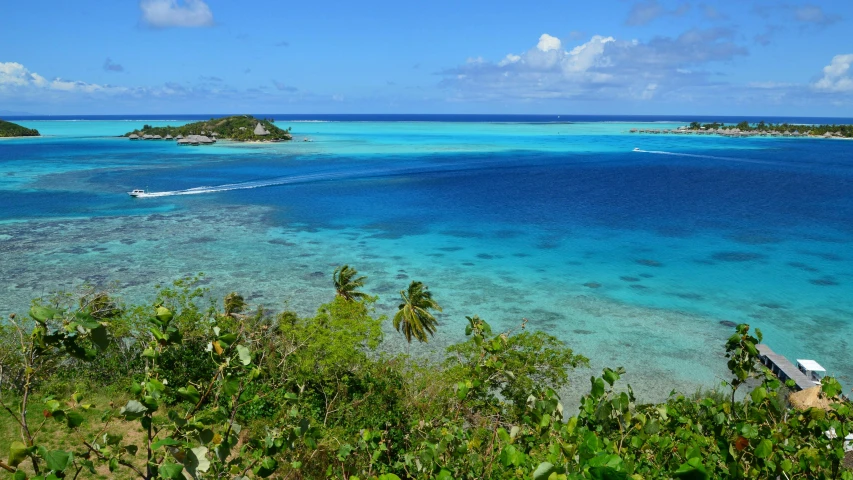 boats floating in the blue sea with islands in the distance