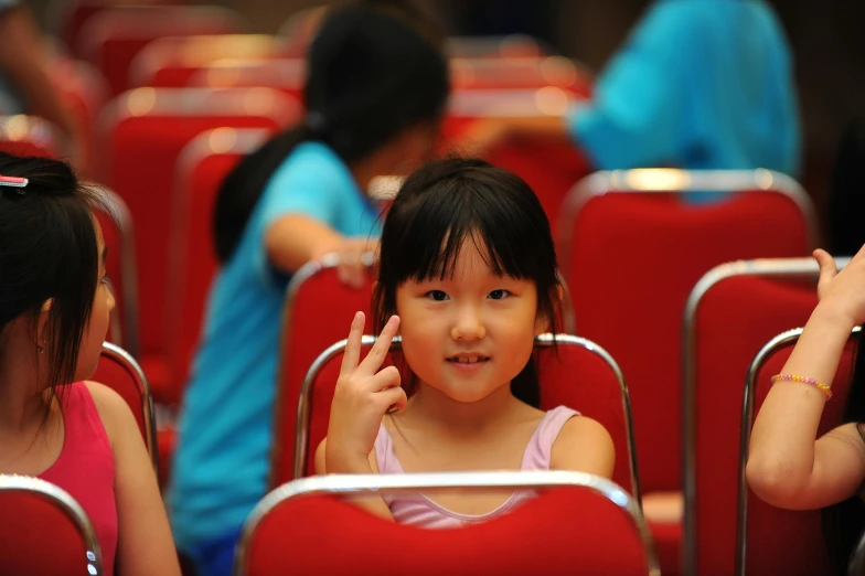 the little girl is sitting in the red chairs