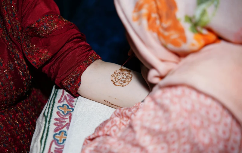 a young woman getting her arm tattooed by someone