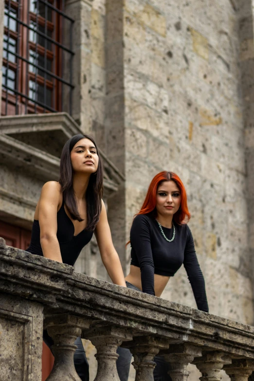 two women posing on a balcony ledge