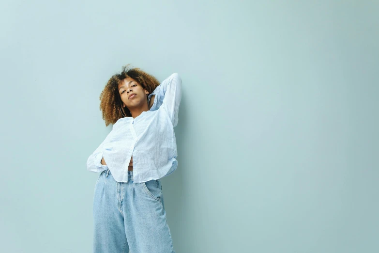 a young woman leaning against a blue wall and looking up