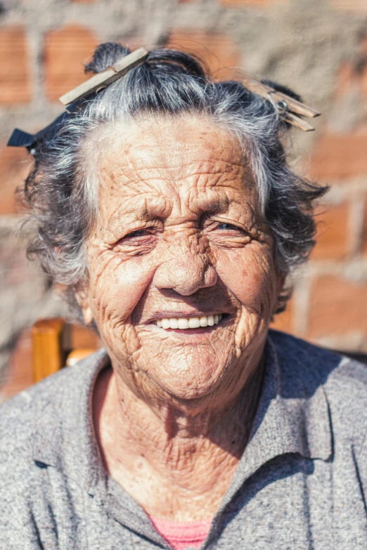 an elderly woman smiles for the camera with birds on her head