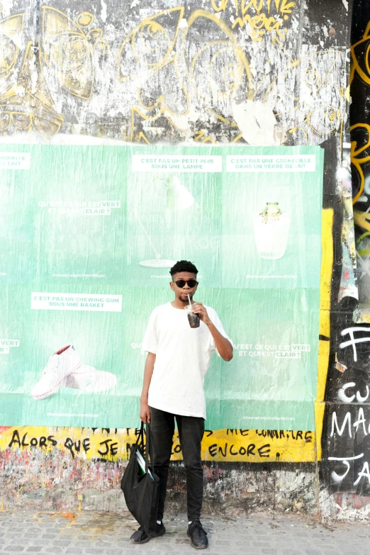 a man standing in front of a wall with a cell phone