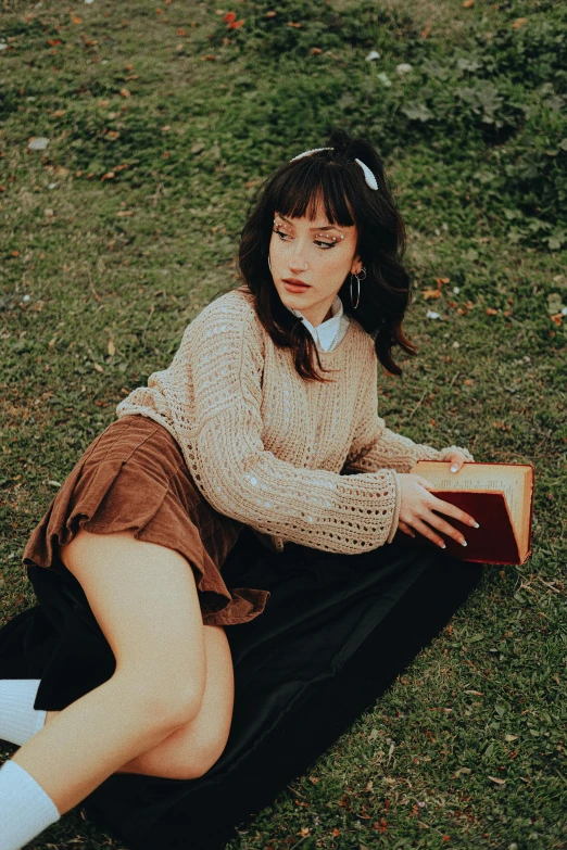 a woman is laying on the grass with her arm in the book