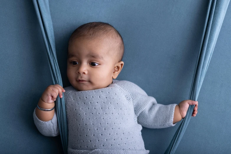 a baby in a sweater holding onto two sticks