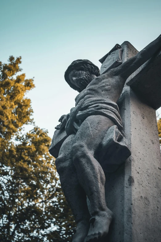 a statue in the shape of a man with a cross is on a pillar