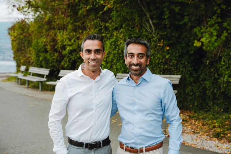 two men smiling at the camera near some benches