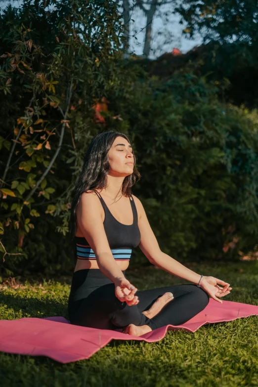 woman doing a yoga pose outdoors with her pink towel