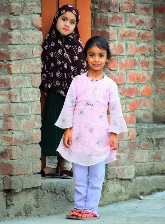 two girls standing outside of the door of an old building