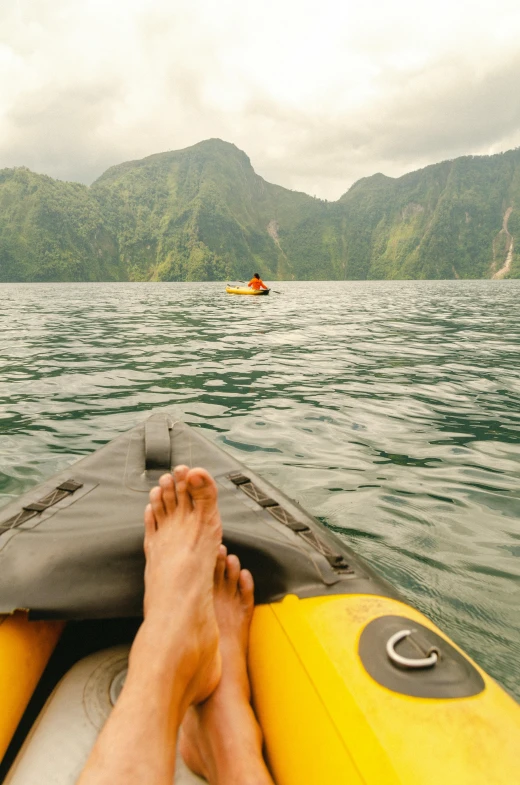a person is kayaking in the ocean with mountains in the background