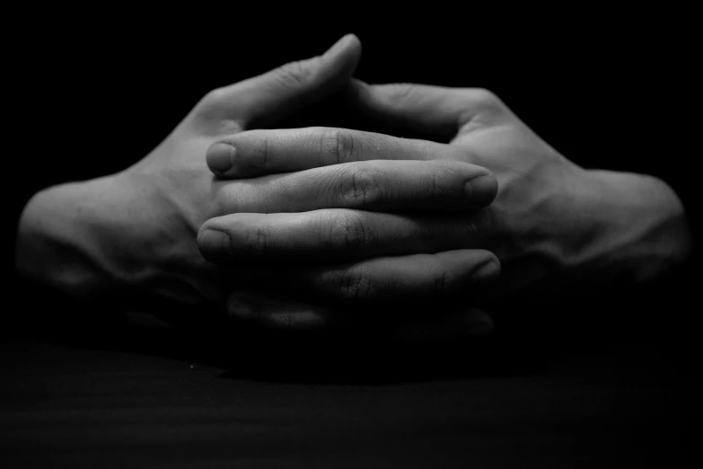black and white image of hands together in the dark