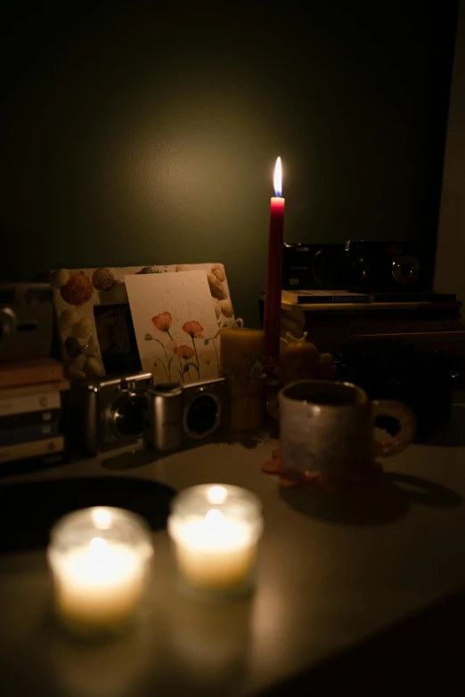 two lit candles on a table with books