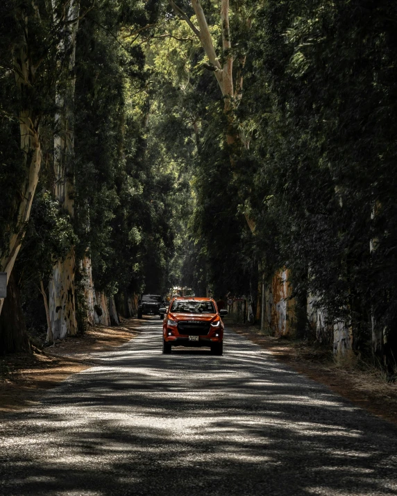 a red sports car driving down a road lined with trees