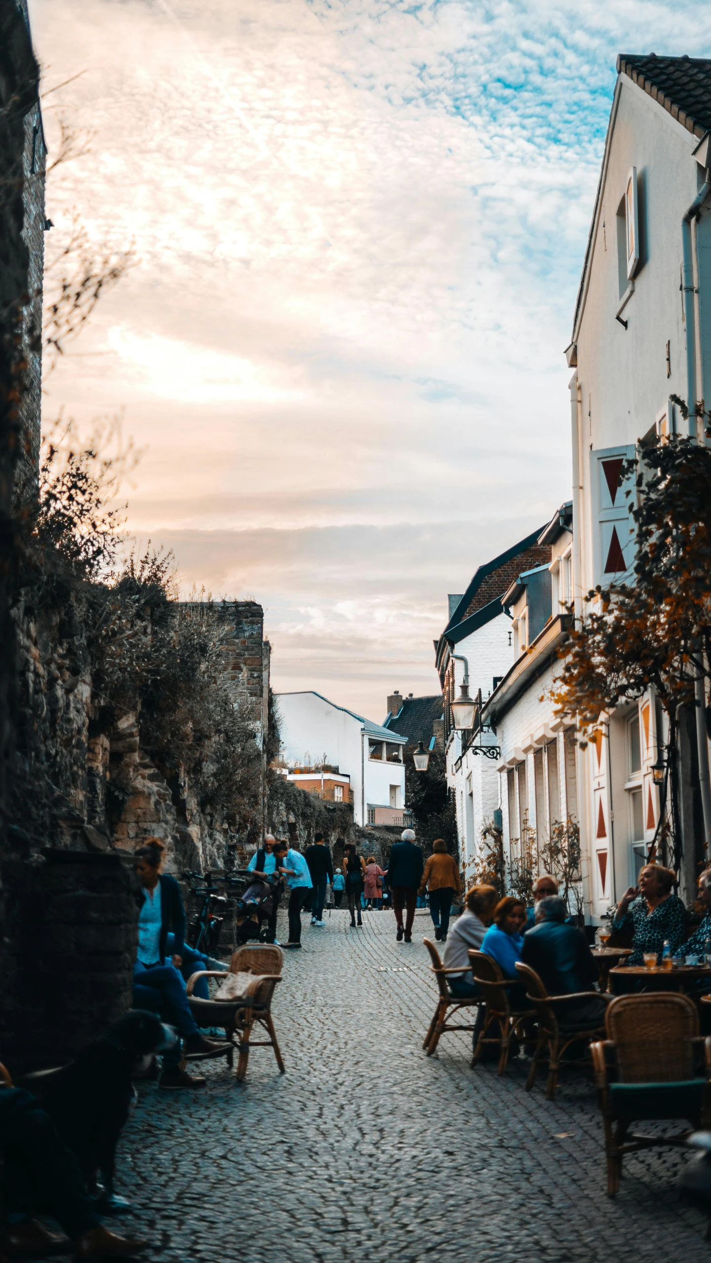 a cobblestone street with many people sitting outside