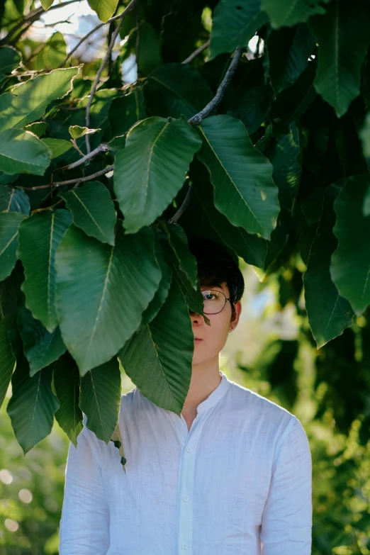 a person wearing sunglasses is behind a tree