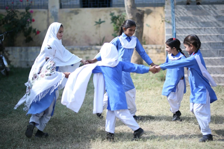 children in historical dress are holding hands and wearing blue dresses