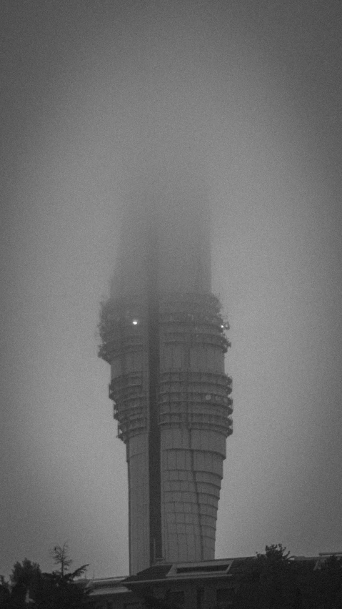 a tall tower in the fog is near trees