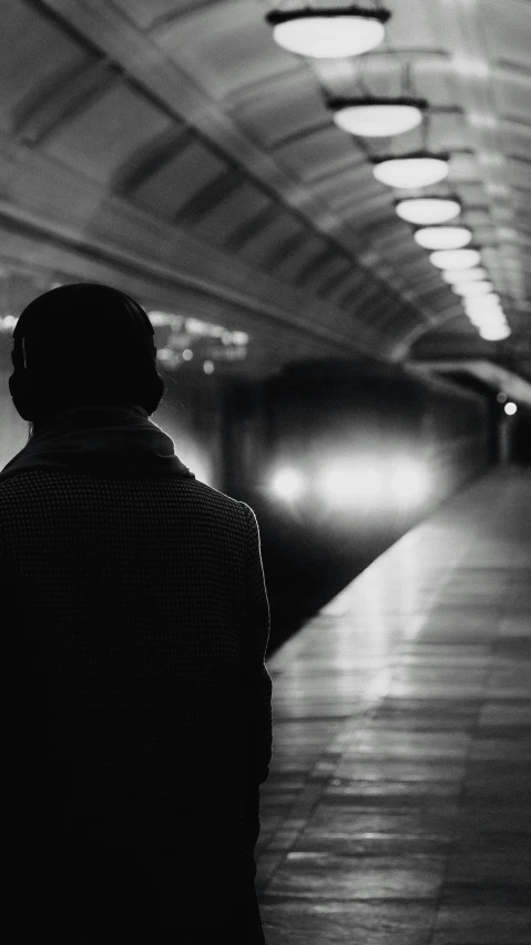 a person sitting on a bench watching a train at a subway station