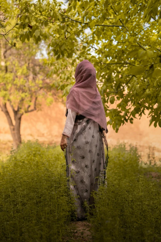 a person wearing a purple jacket standing under a tree