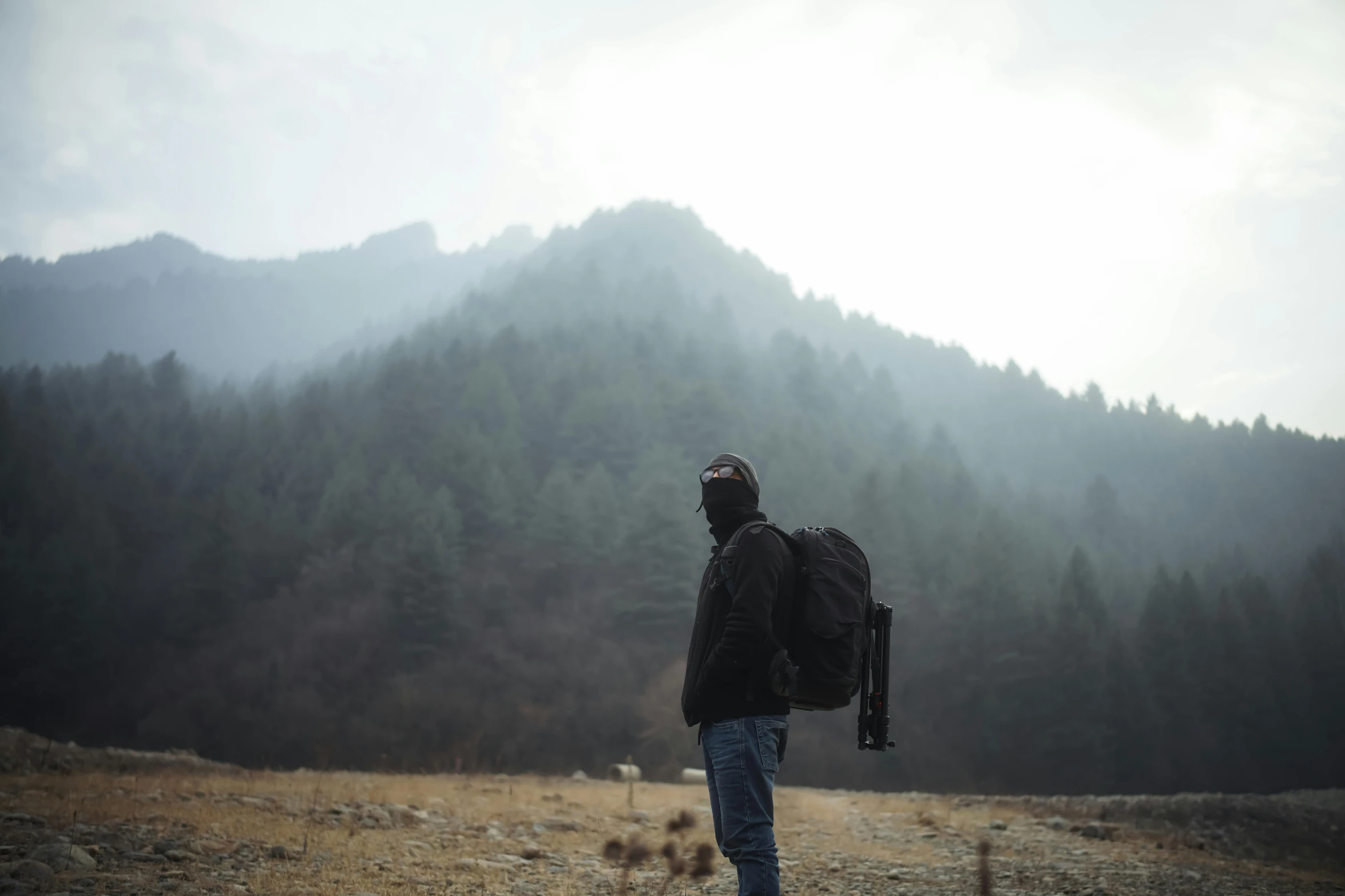 there is a man standing in a grassy field with backpack on