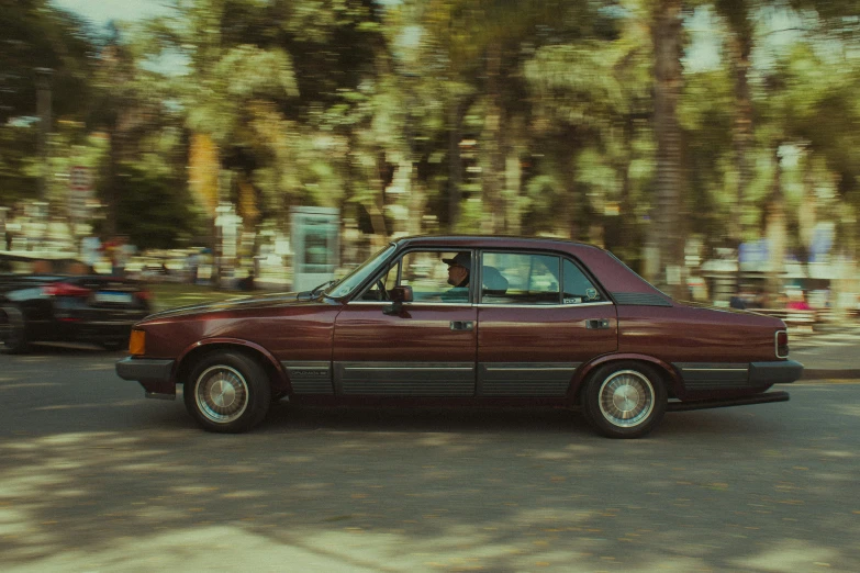 a maroon car is moving along the street