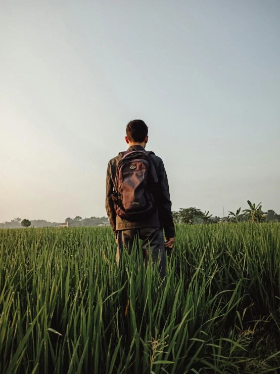 a young man standing in a large green field