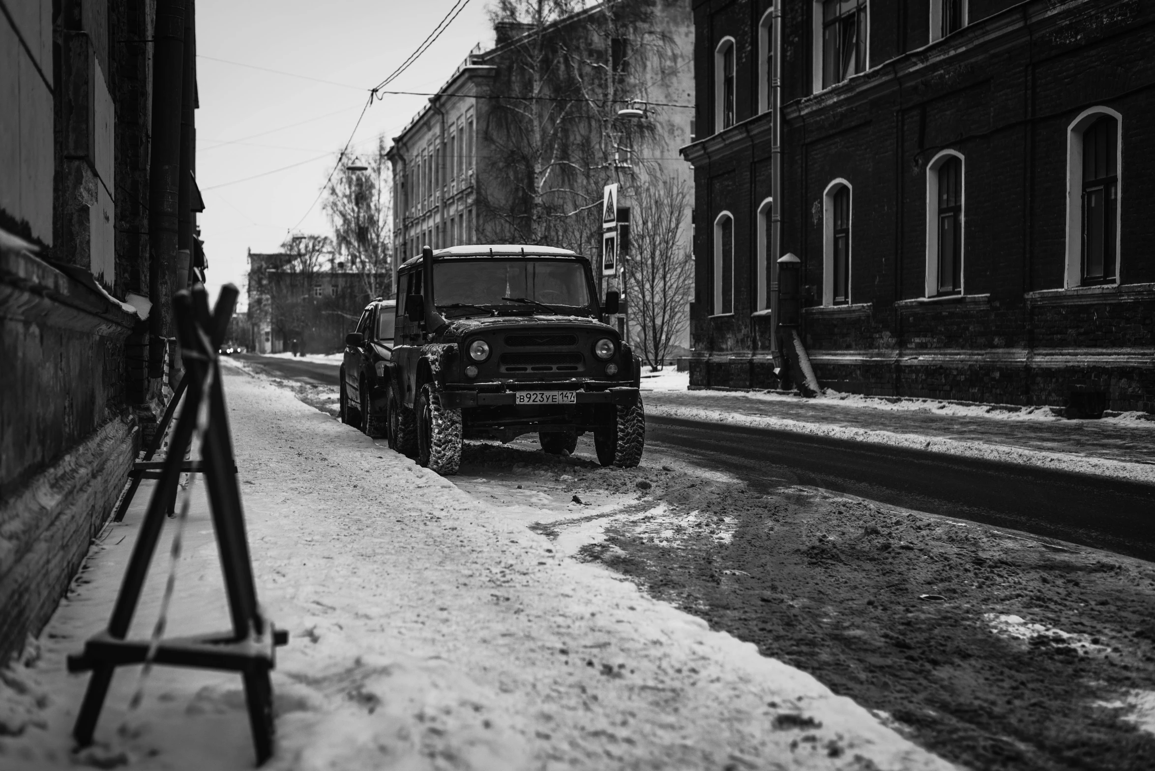 a jeep parked on snow covered street in front of a building