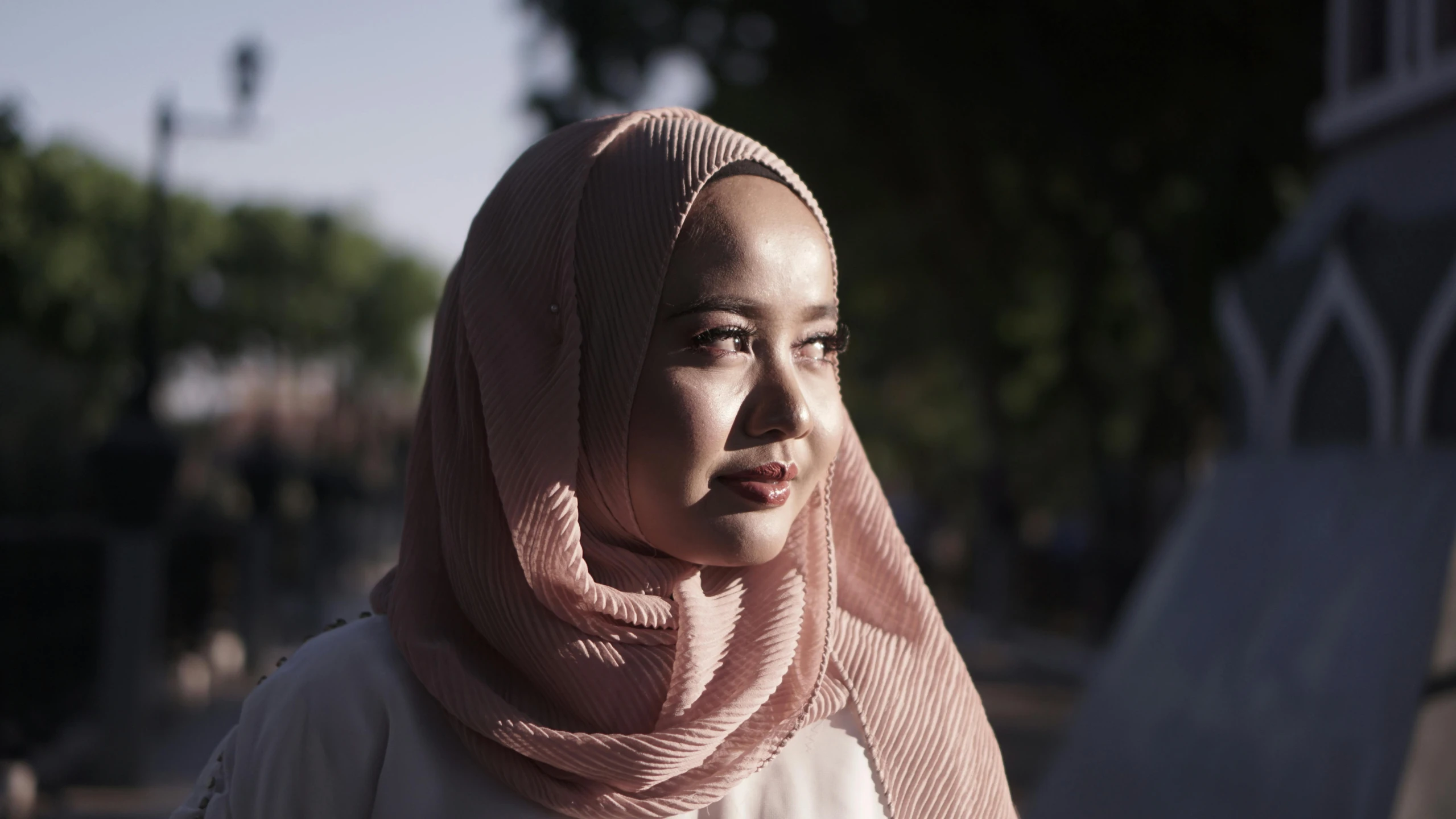 an asian woman standing near a bench in front of a lamp post