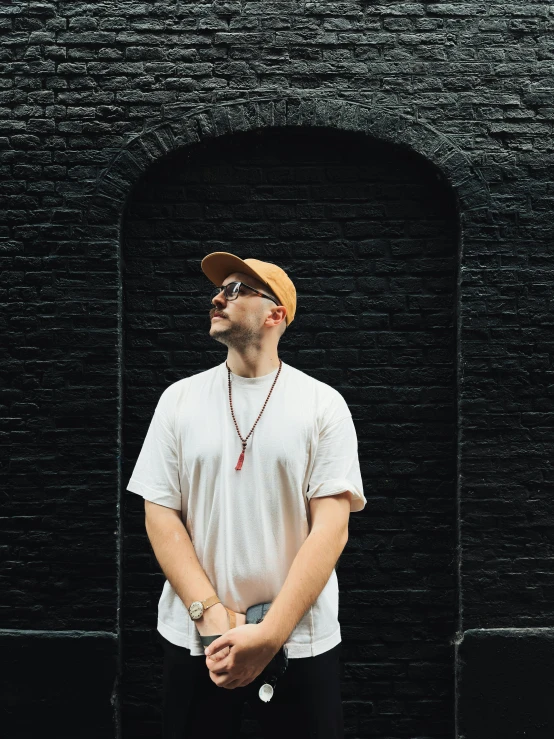 a man standing in front of a brick wall