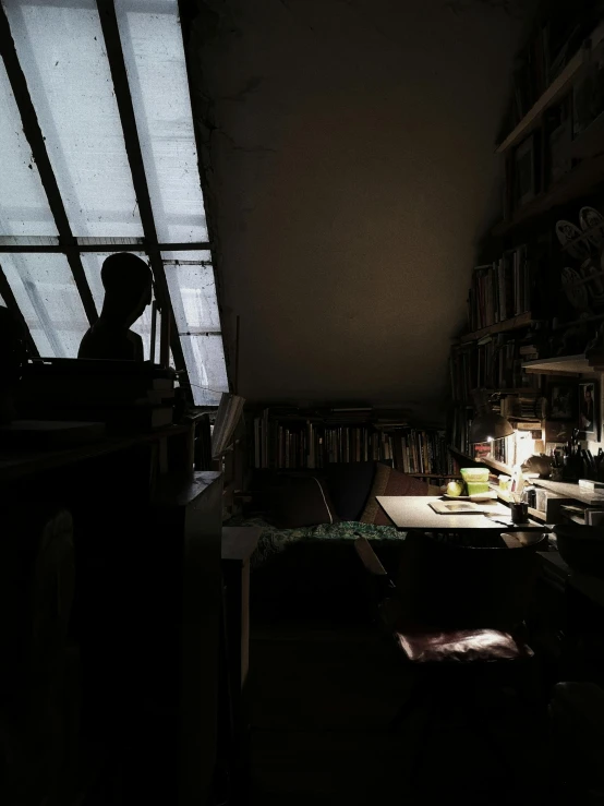 a dark room has shelves, a table and a lamp