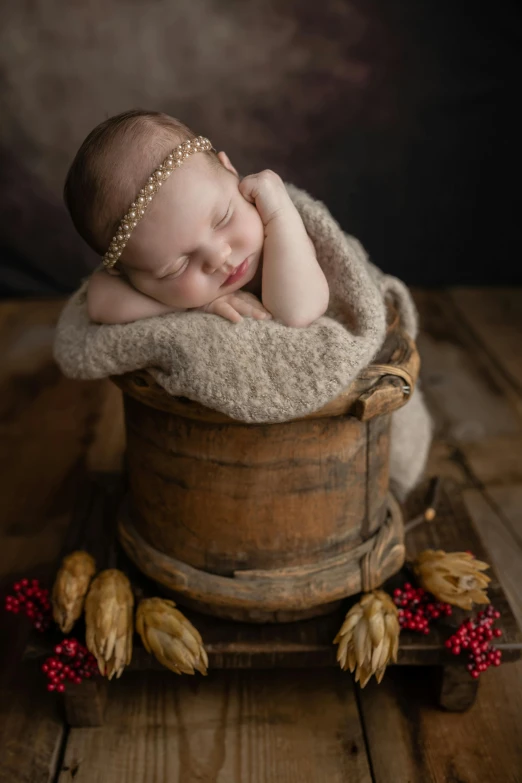 a baby sleeping in a bucket on a wooden table