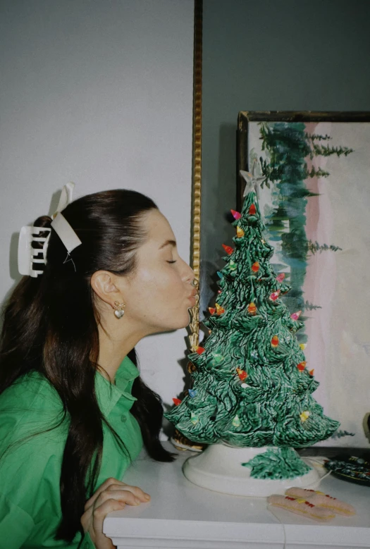 the girl is kissing the small christmas tree
