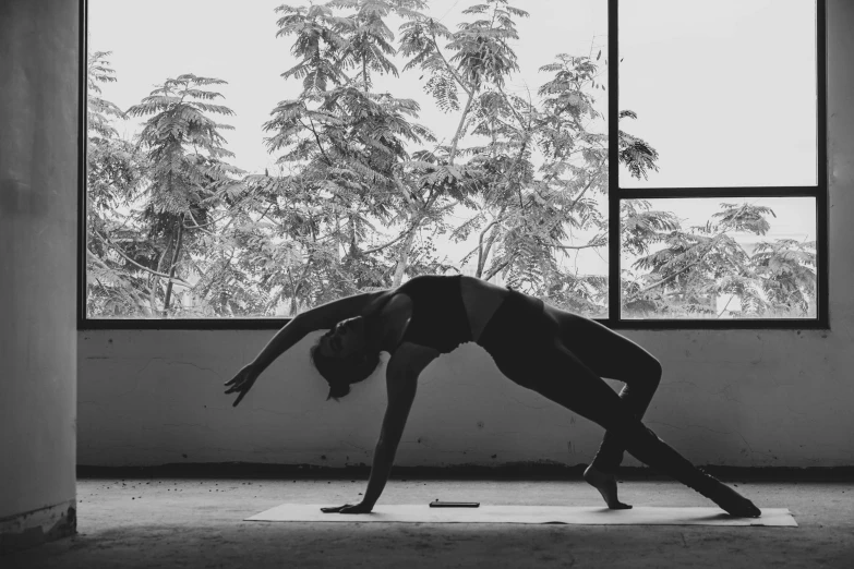 a woman performing yoga in a building while looking out a window