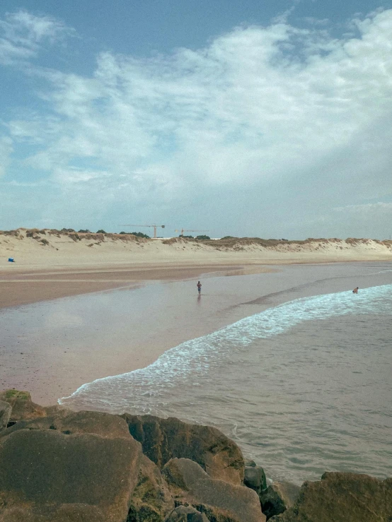 a beach with a few people in it and waves