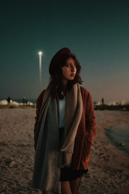 a woman in boots is standing on the beach at night