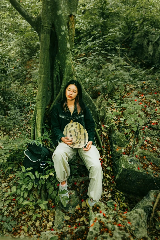 a woman sitting in the middle of a forest holding an animal